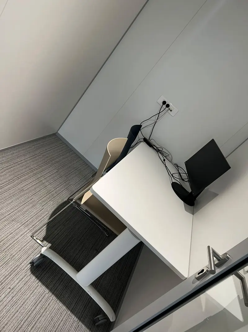 Bureau dans une petite pièce avec moquette grise et murs blancs