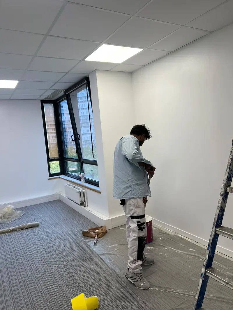 Peintre au travail dans un bureau, sol de moquette protégé